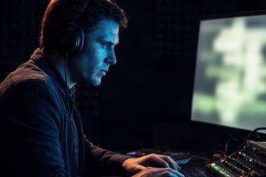 Hicran Sümer monteert podcastaudio met koptelefoon in een donkere editruimte